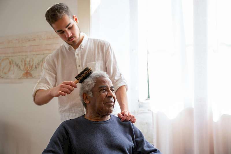Home care aide brushing the hair of an elderly man