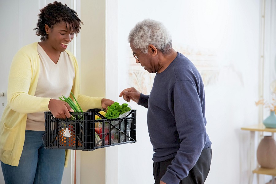 Live-in caregiver bringing food to elderly man's home